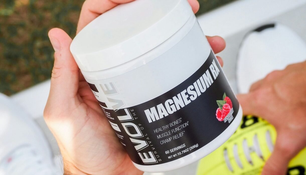Hand holding a tub of magnesium supplement for energy and muscle recovery