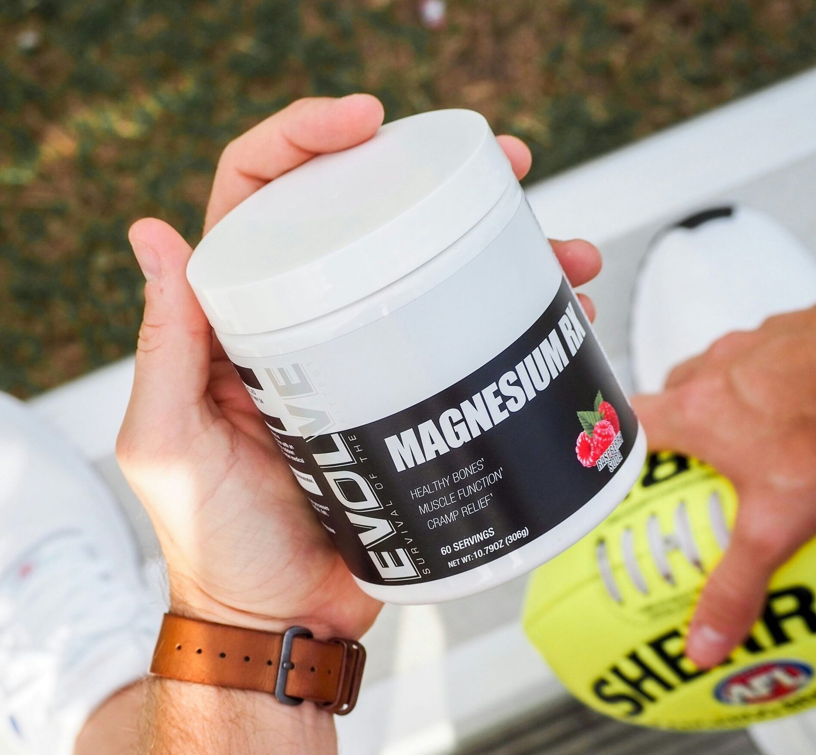 Hand holding a tub of magnesium supplement for energy and muscle recovery
