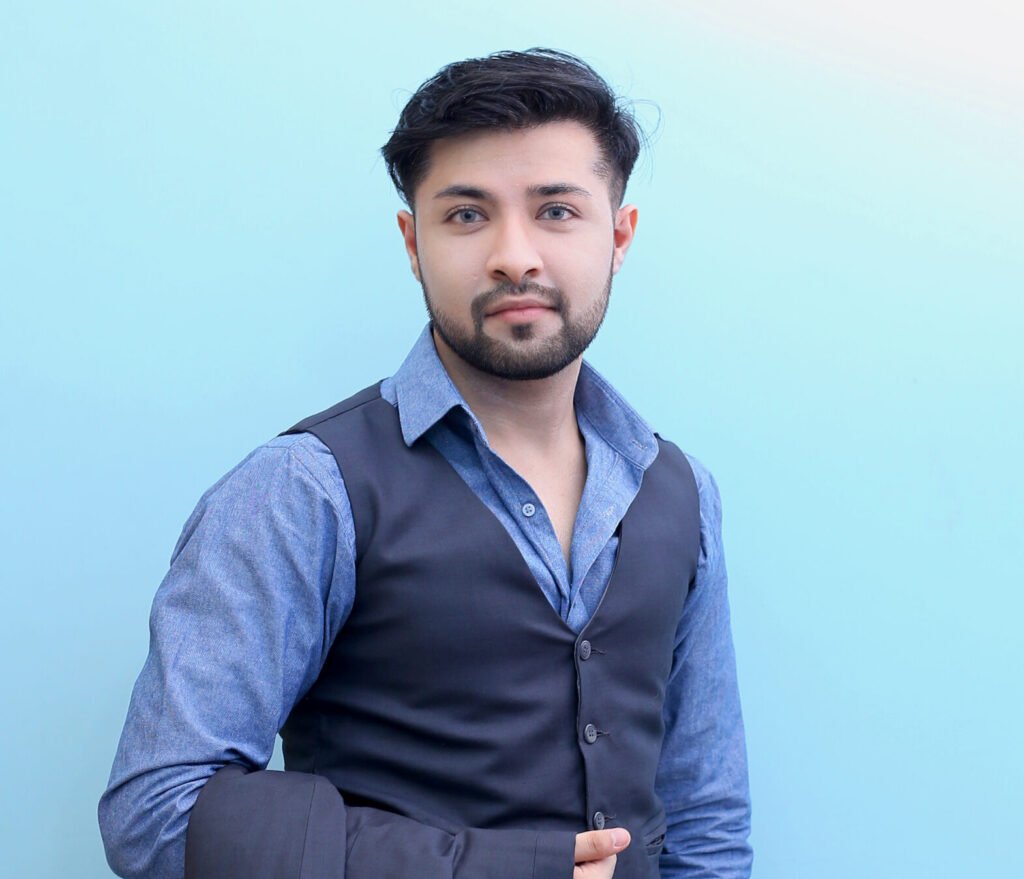 Dr. Hasnain Siraj Memon in a grey waistcoat and dress shirt, holding a suit coat and smiling confidently