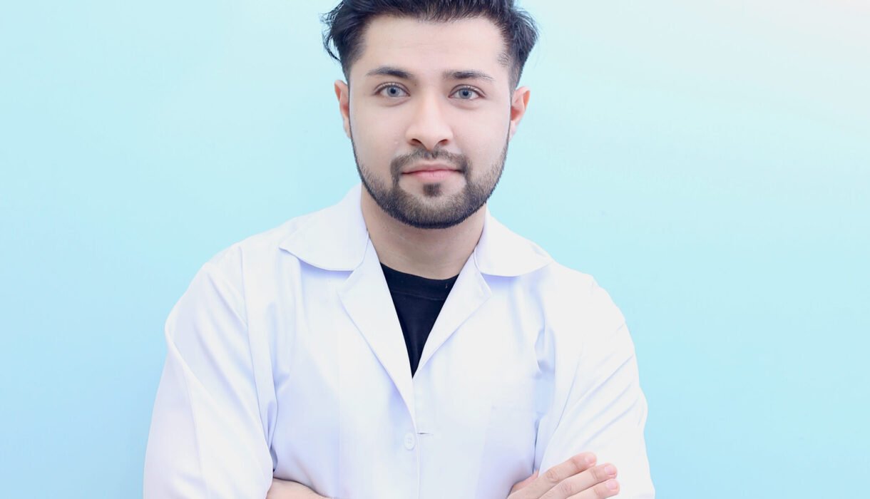Dr. Hasnain Siraj Memon wearing a lab coat with arms crossed and a confident smile