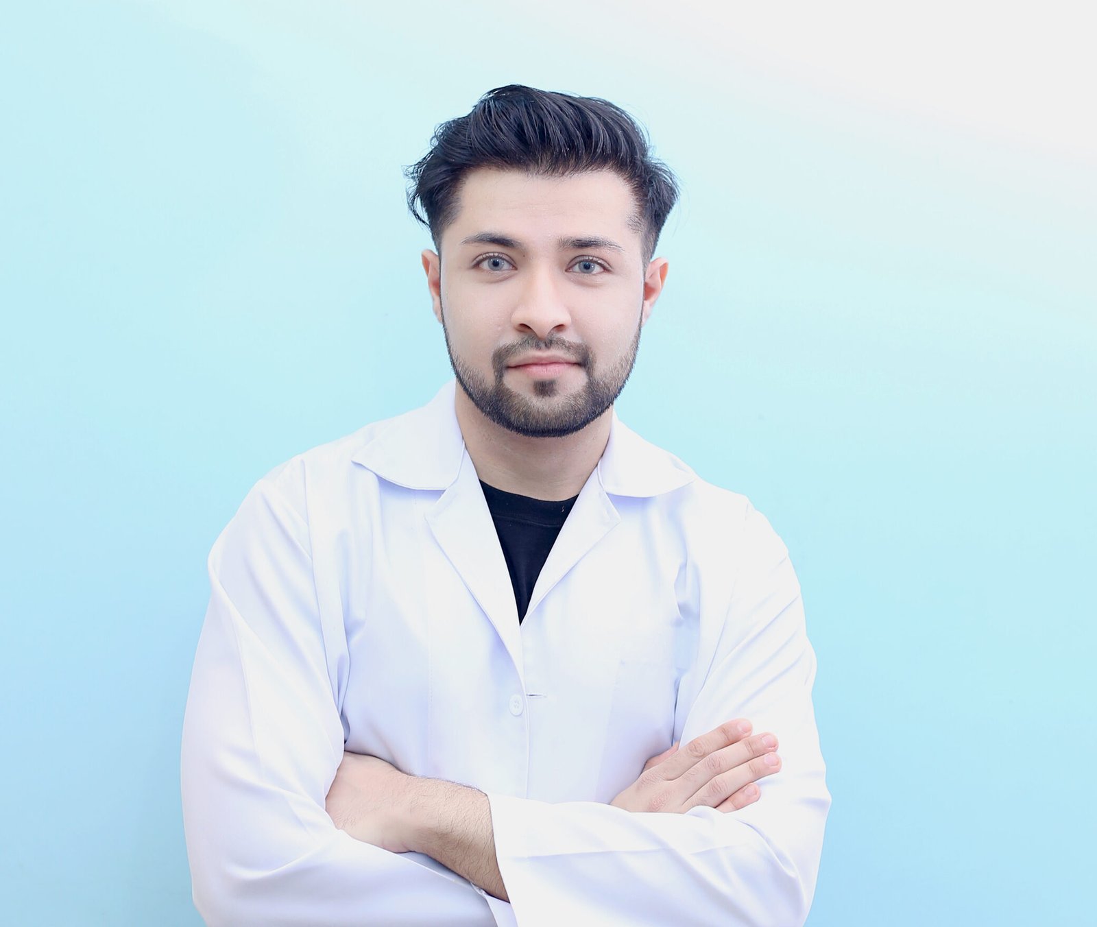 Dr. Hasnain Siraj Memon wearing a lab coat with arms crossed and a confident smile