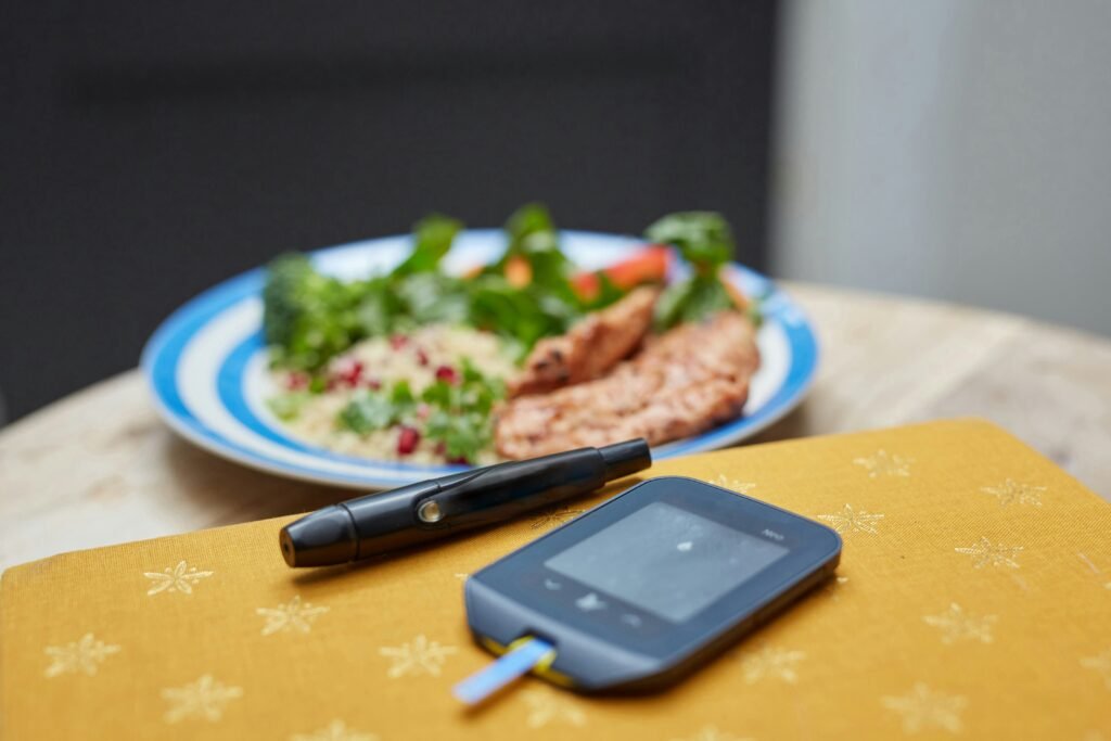 Glucometer placed beside a plate of healthy balanced meal for monitoring post-meal blood sugar.