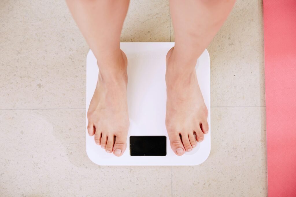 Person standing on a digital weighing scale to track body composition and progress.